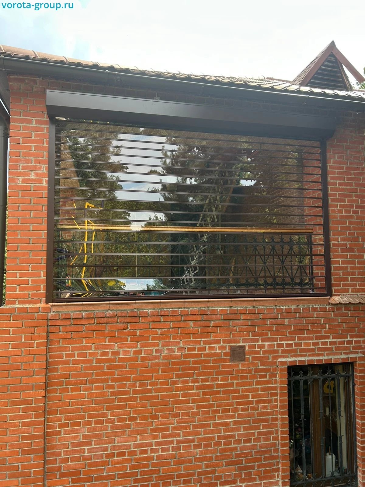 Прозрачные рольставни для второго этажа кирпичного дома с кованым ограждением внутри